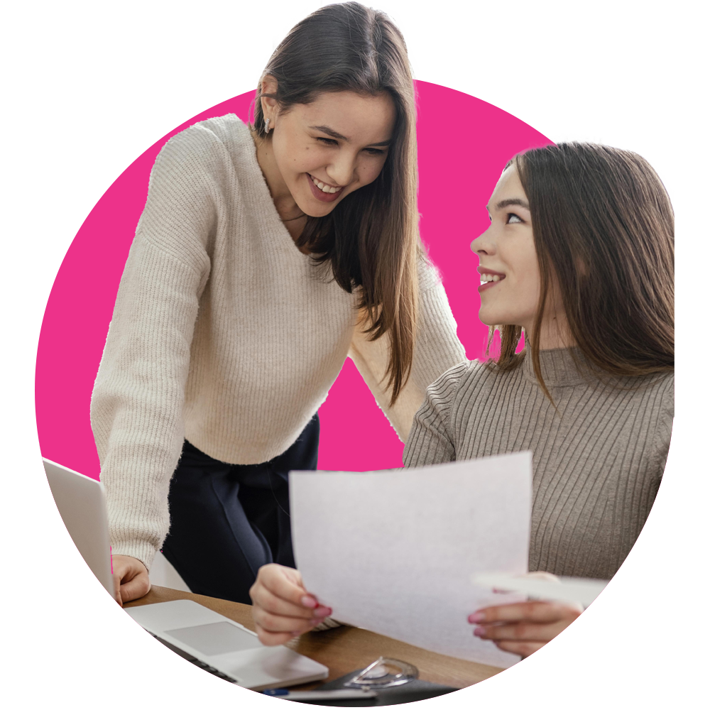 Dos mujeres sonriendo mientras ven información en una hoja.